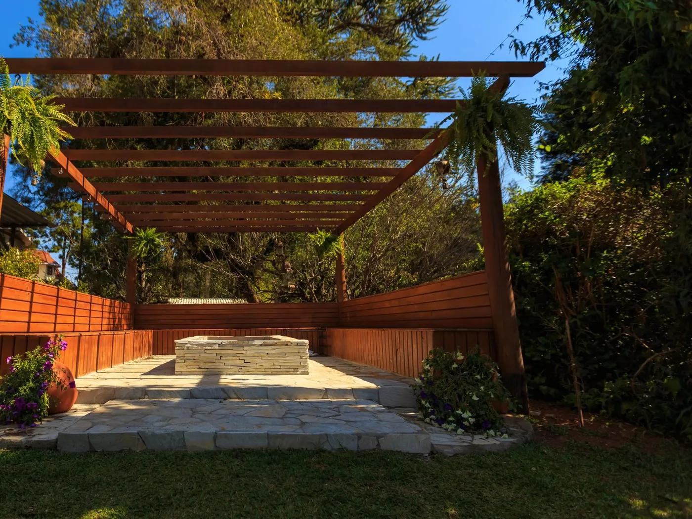 A cedar pergola over a stone patio, enclosed by a horizontal cedar fence